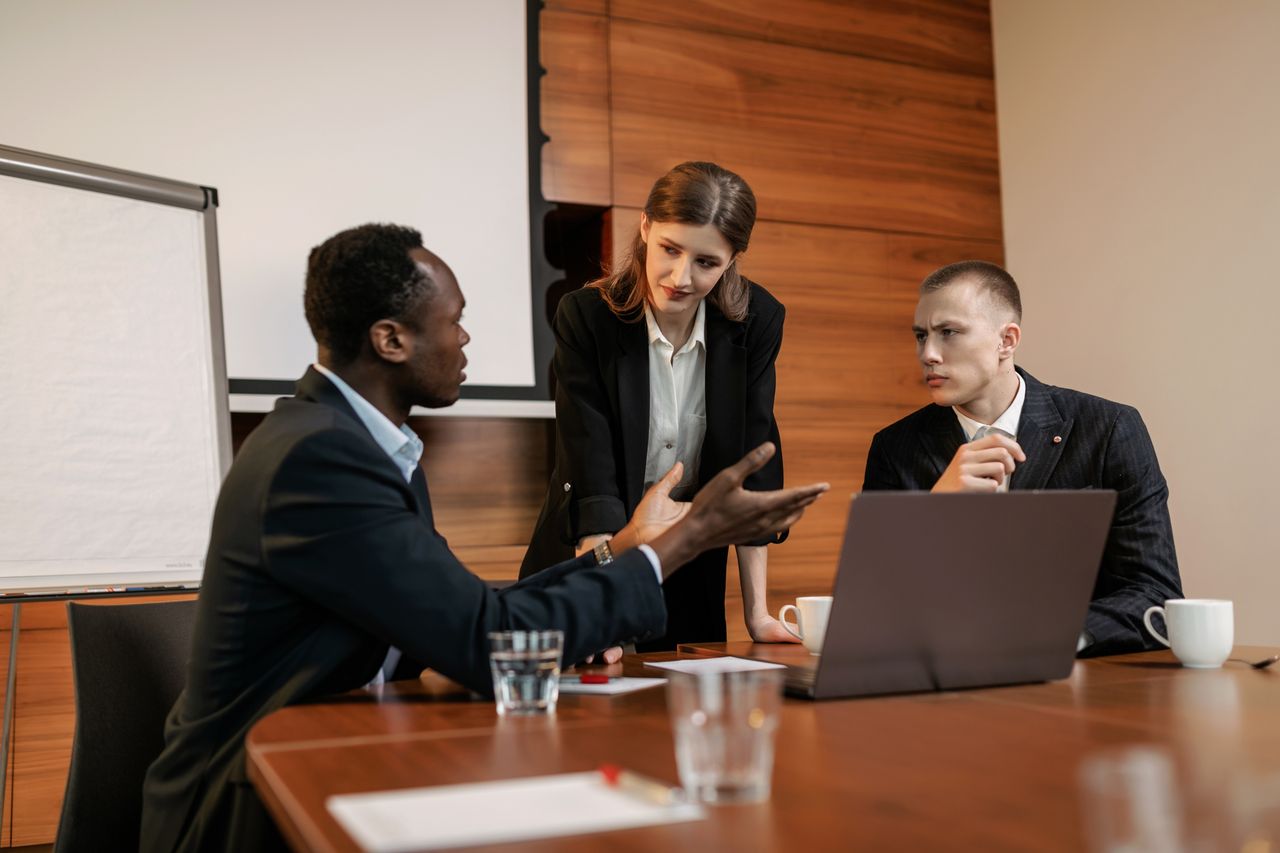 Three colleagues engaged in a serious business meeting discussing ideas.